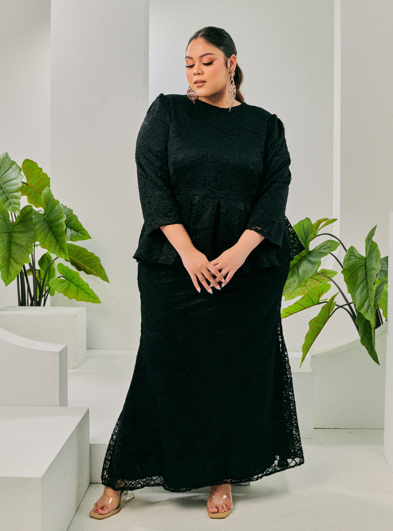 A woman dressed in Black Tun Rozi Peplum Kurung