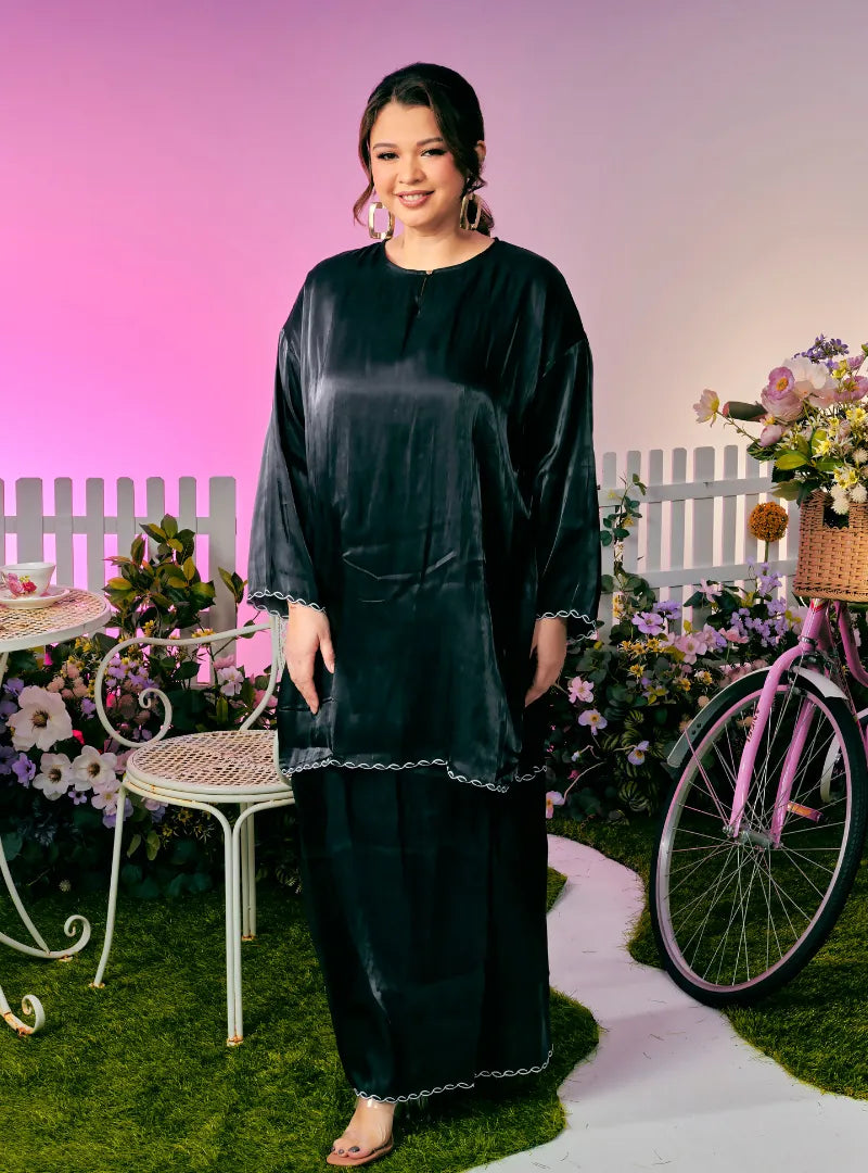 A woman dressed in Black Tun Seroja Satin Kurung Pahang