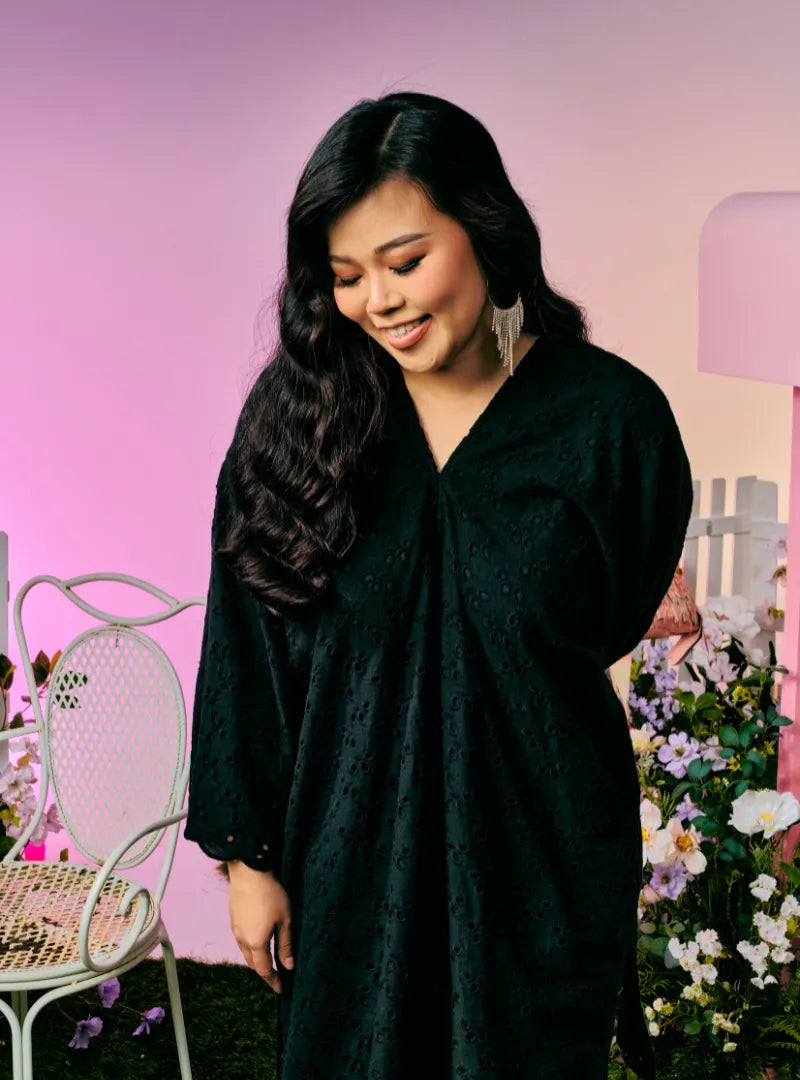 A woman dressed in Black Tun Yasmin Eyelet Oversized Kurung