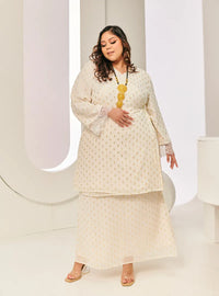 A woman dressed in Champagne Tun Tipah Dotted Wrap Kurung