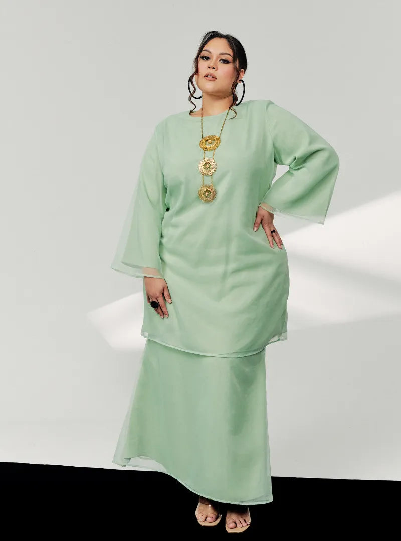 A woman in dressed in Mint Green Tun Sharimah Organza Kurung