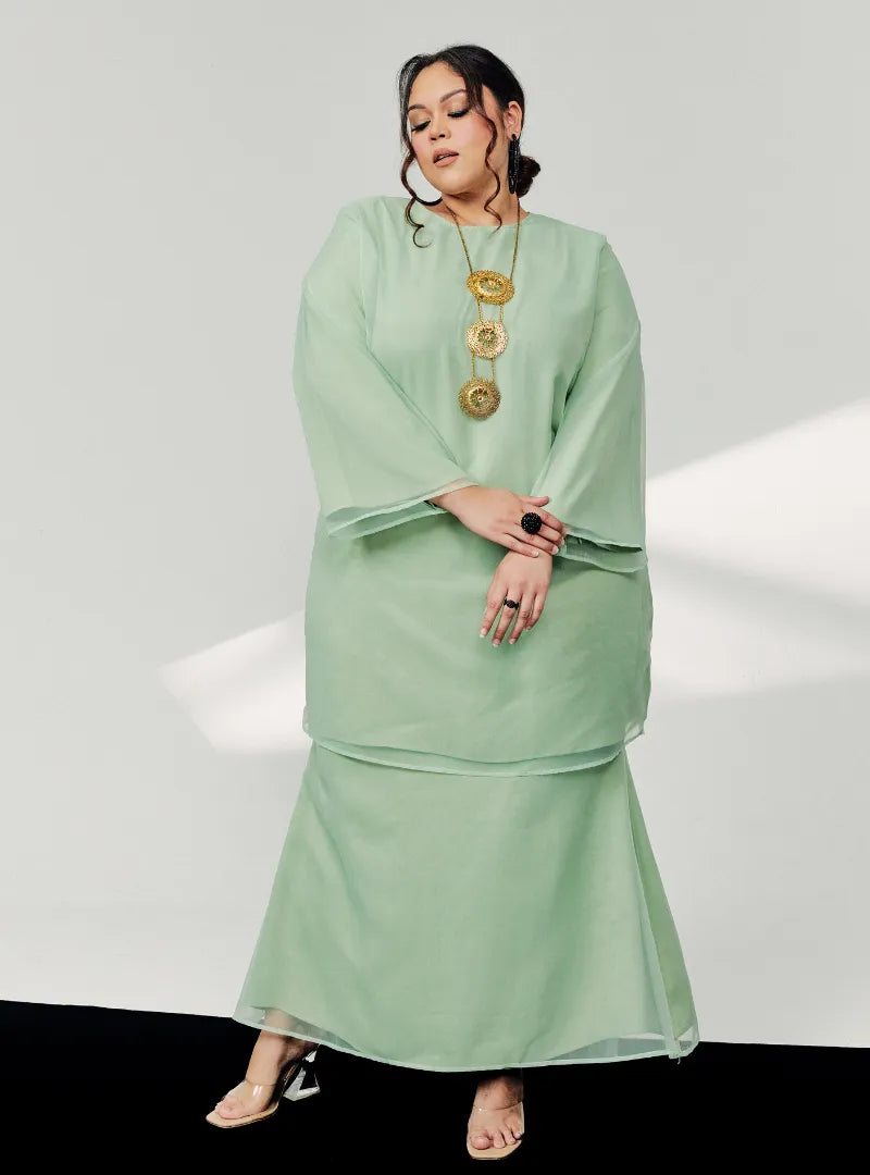 A woman in dressed in Mint Green Tun Sharimah Organza Kurung