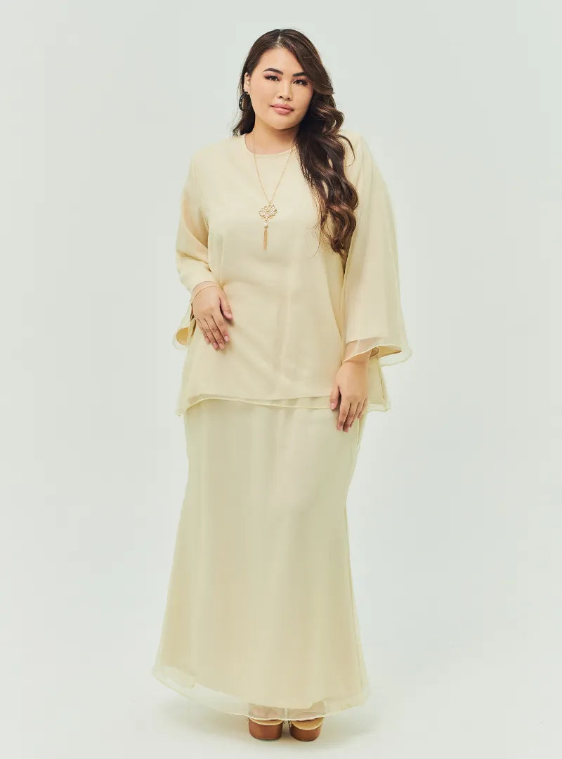A woman dressed in Nude Sand Tun Aminah Organza Basic Kurung