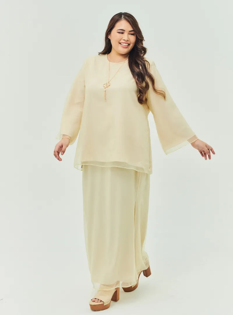 A woman dressed in Nude Sand Tun Aminah Organza Basic Kurung