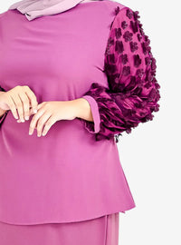 A woman dressed in Raisin High Neck Butterfly Kurung
