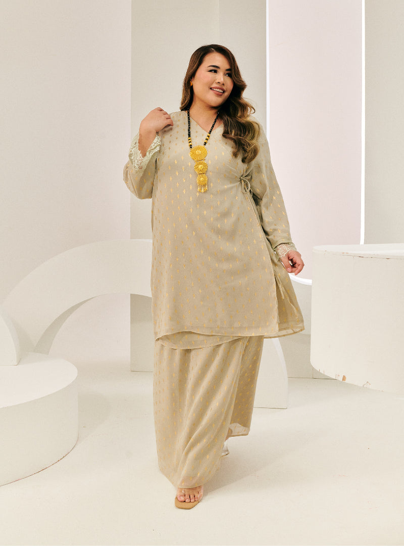 A woman dressed in Sage Tun Tipah Dotted Wrap Kurung